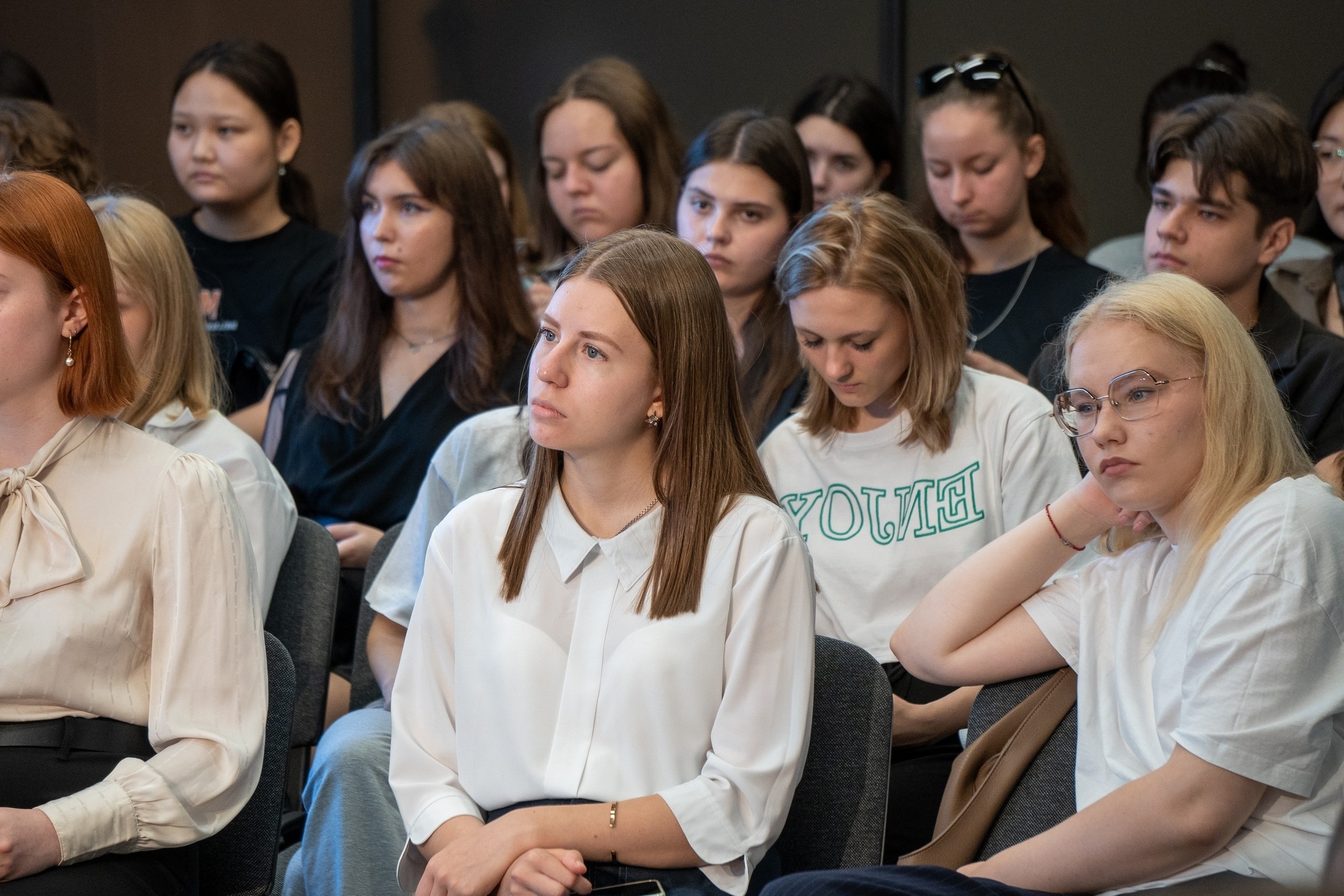 Группа студентов внимательно слушает выступление в аудитории.