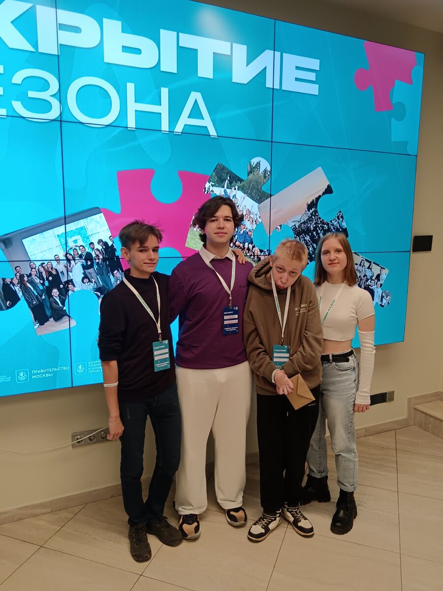 Четверо студентов с бейджами позируют на фоне большого экрана с надписью «ОТКРЫТИЕ СЕЗОНА» и логотипом Правительства Москвы